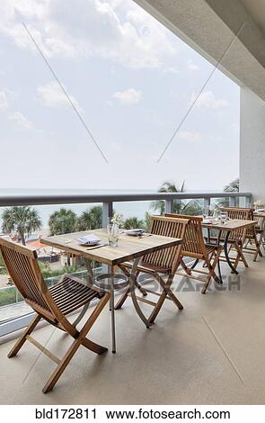 Stock Image - Empty tables on restaurant balcony. Fotosearch