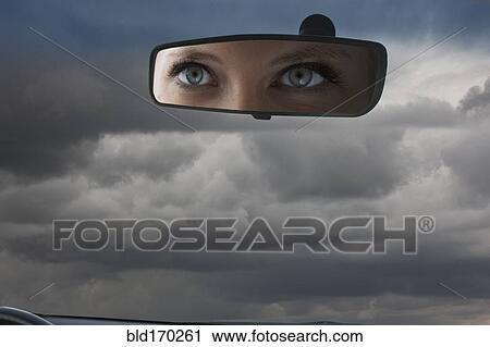 Stock Image - Eyes of Caucasian woman reflecting in rear view mirror. Fotosearch