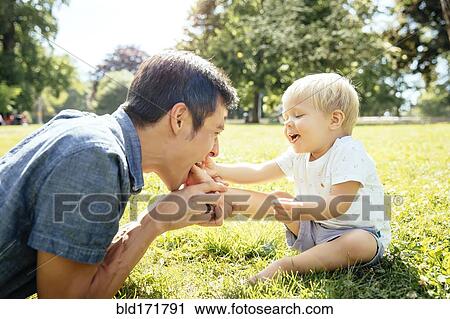 Father and son playing in grass in park View Large Photo Image Stock Image - Father and son playing in grass in park. Fotosearch