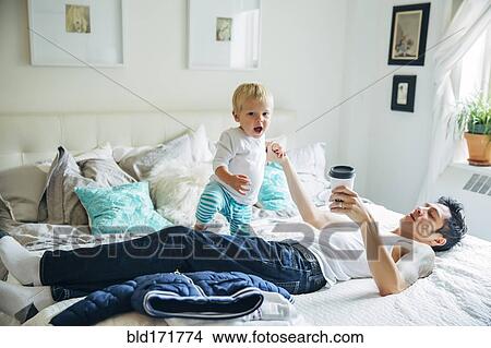 Picture - Father and son playing on bed. Fotosearch