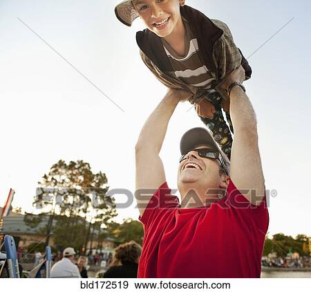 Stock Photo - Father lifting son under blue sky. Fotosearch