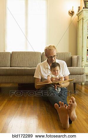 Stock Photo - Father reading to son on living room floor. Fotosearch