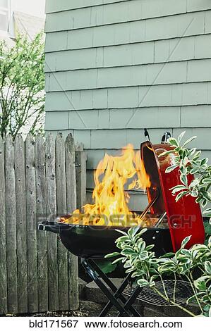 Stock Photo - Fire burning on grill in backyard. Fotosearch