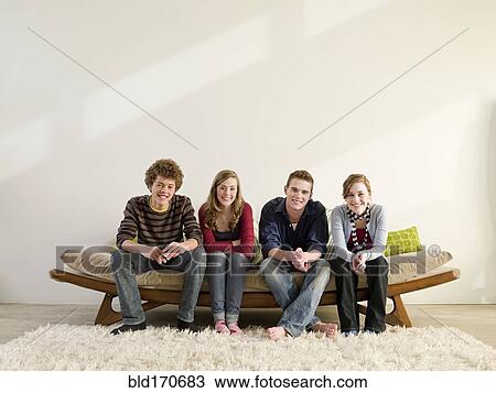 Stock Image - Friends sitting on modern sofa in living room. Fotosearch
