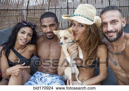Picture - Friends smiling with dog in cabana. Fotosearch