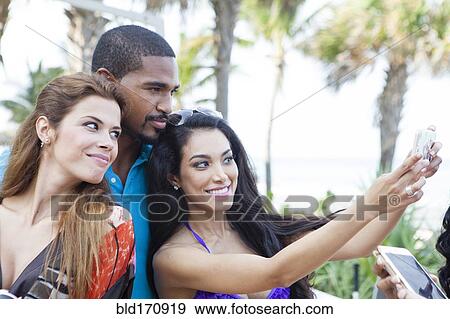 Friends taking selfie with cell phone outdoors View Large Photo Image Stock Photo - Friends taking selfie with cell phone outdoors. Fotosearch