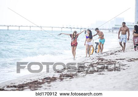 Friends walking in waves on beach View Large Photo Image Stock Image - Friends walking in waves on beach. Fotosearch