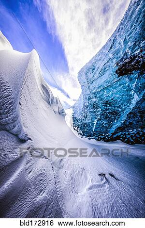Stock Photograph - Glass wall of snowy ice cave. Fotosearch