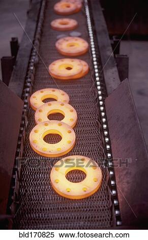 Stock Photography - Glowing metal manufactured pieces on conveyor belt. Fotosearch