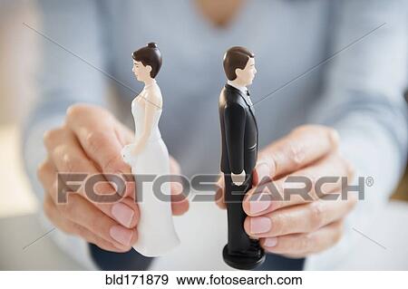 Stock Photo - Hands holding bride and groom cake toppers. Fotosearch