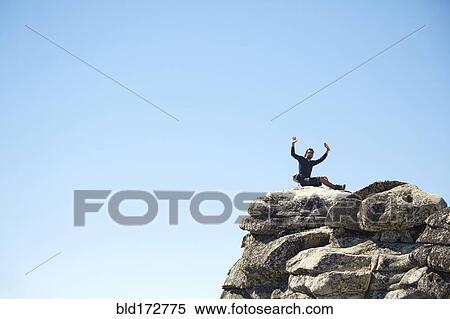 Hiker cheering on rocky hilltop under blue sky View Large Photo Image Stock Photography - Hiker cheering on rocky hilltop under blue sky. Fotosearch