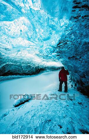 Picture - Hiker walking in ice cave. Fotosearch