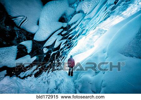 Stock Photography - Hiker walking in ice cave. Fotosearch