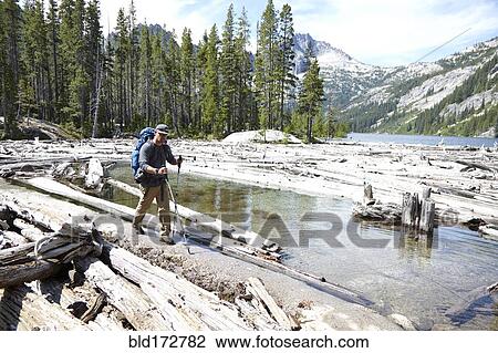 Stock Image - Hiker walking on dirt path by remote lake. Fotosearch