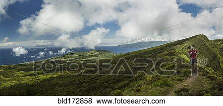 Hiker walking on hilltop dirt path over Cabeco Gordo crater, Faial, Portugal View Large Photo Image Stock Photo - Hiker walking on hilltop dirt path over Cabeco Gordo crater, Faial, Portugal. Fotosearch