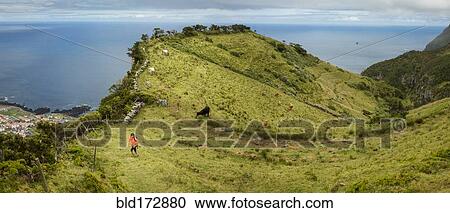 Stock Image - Hiker walking on hilltop path in rural landscape. Fotosearch