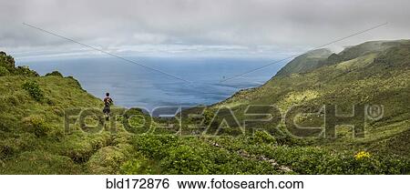 Stock Photograph - Hiker walking on hilltop path in rural landscape. Fotosearch