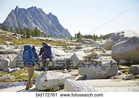 Hikers backpacking in rocky rural landscape View Large Photo Image Stock Image - Hikers backpacking in rocky rural landscape. Fotosearch