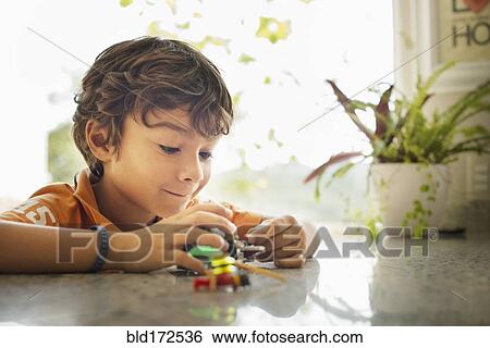 Stock Photograph - Hispanic boy playing with toy cars on counter. Fotosearch
