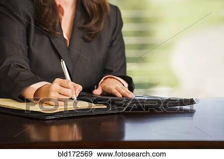 Hispanic businesswoman writing notes at desk View Large Photo Image Stock Photo - Hispanic businesswoman writing notes at desk. Fotosearch