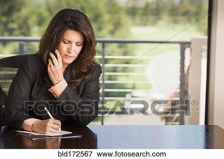 Hispanic businesswoman writing notes in office View Large Photo Image Stock Photo - Hispanic businesswoman writing notes in office. Fotosearch
