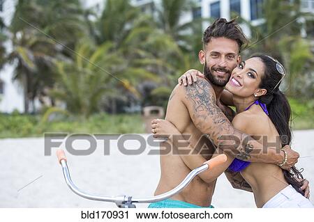 Hispanic couple hugging on bicycle on urban beach View Large Photo Image Stock Image - Hispanic couple hugging on bicycle on urban beach. Fotosearch