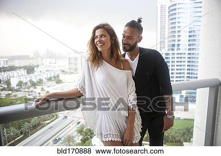 Stock Photo - Hispanic couple standing on urban balcony. Fotosearch