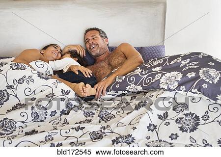 Stock Photography - Hispanic family playing in bed. Fotosearch