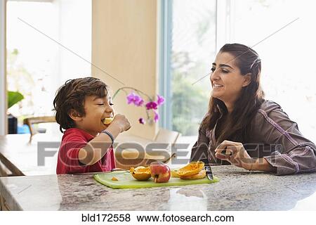 Hispanic mother and son eating fruit in kitchen View Large Photo Image Stock Photo - Hispanic mother and son eating fruit in kitchen. Fotosearch