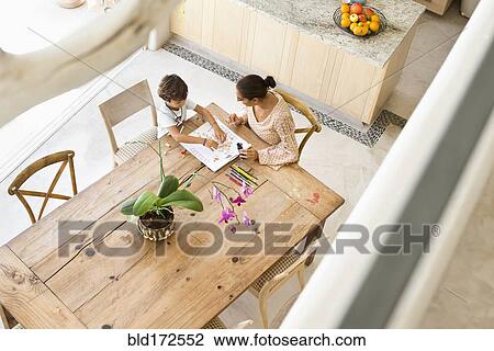 Stock Image - Hispanic mother and son playing game at table. Fotosearch