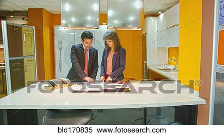 Stock Photography - Hispanic salesman showing client samples in kitchen. Fotosearch