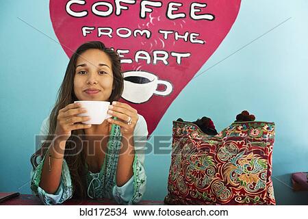 Picture - Hispanic woman drinking coffee in cafe. Fotosearch