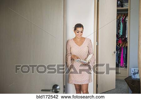 Stock Image - Hispanic woman holding journal in closet. Fotosearch