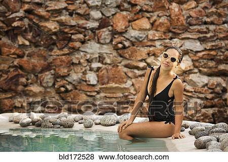 Stock Photo - Hispanic woman sitting in swimming pool. Fotosearch