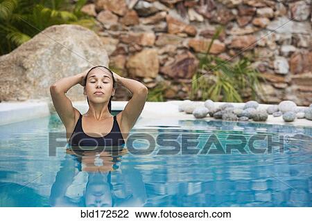 Stock Image - Hispanic woman swimming in pool. Fotosearch