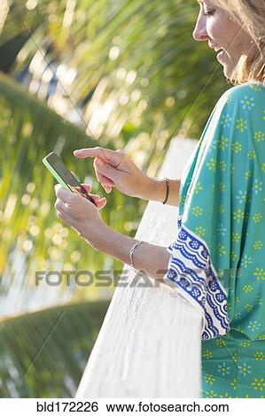 Hispanic woman using cell phone on patio View Large Photo Image Stock Photograph - Hispanic woman using cell phone on patio. Fotosearch