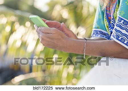 Stock Photography - Hispanic woman using cell phone outdoors. Fotosearch
