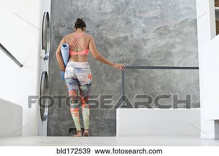 Stock Photo - Hispanic woman wearing workout gear in modern living room. Fotosearch