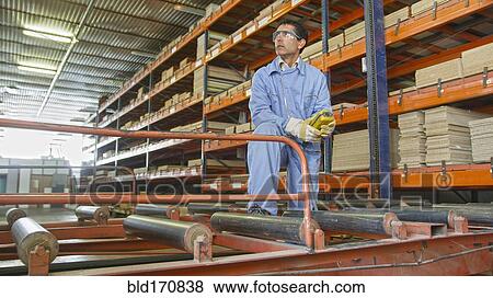 Stock Photo - Hispanic worker checking inventory in factory. Fotosearch