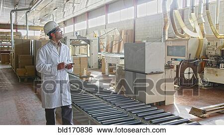 Stock Photograph - Hispanic worker checking production line in factory. Fotosearch