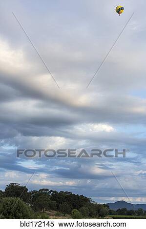 Stock Photography - Hot air balloon flying over rural landscape. Fotosearch