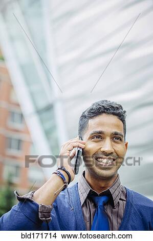 Indian businessman talking on cell phone outdoors View Large Photo Image Picture - Indian businessman talking on cell phone outdoors. Fotosearch