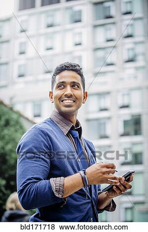 Stock Photo - Indian businessman using cell phone outdoors. Fotosearch