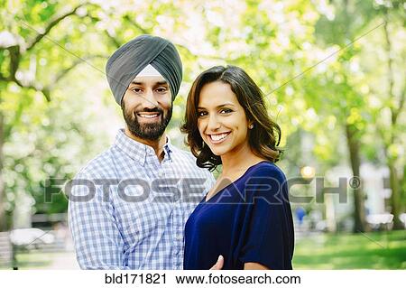 Stock Image - Indian couple hugging in urban park. Fotosearch