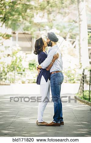 Stock Image - Indian couple kissing in urban park. Fotosearch