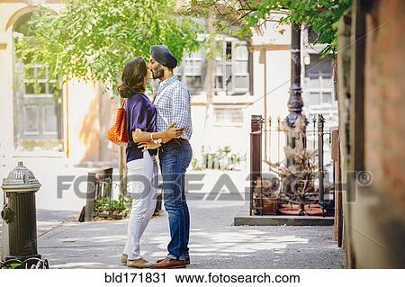 Stock Image - Indian couple kissing on city sidewalk. Fotosearch