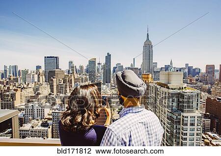 Stock Image - Indian couple taking cell phone photograph of New York cityscape, New York, United States. Fotosearch