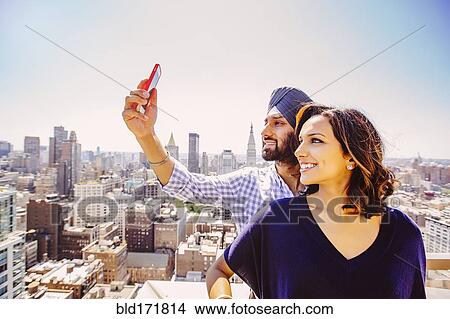 Picture - Indian couple taking selfie over New York cityscape, New York, United States. Fotosearch