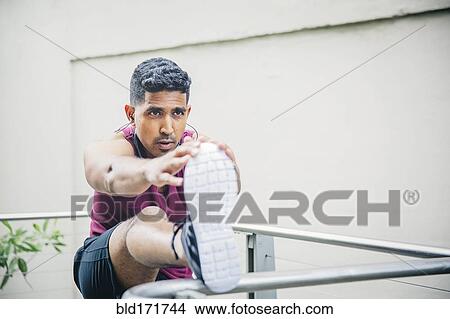 Picture - Indian man stretching on banister. Fotosearch