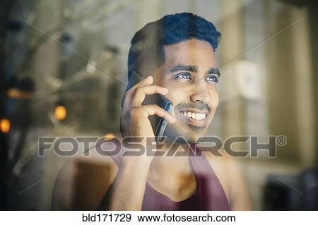 Stock Photo - Indian man talking on cell phone in cafe. Fotosearch